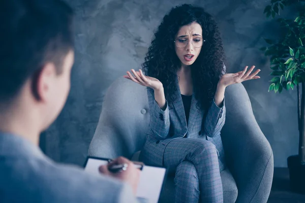 Portrait of her she nice attractive devastated wavy-haired girl sitting in chair talking to doctor expert specialist psychologist anti depression complex concrete wall background work place station