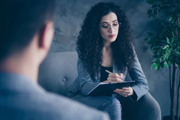 Portrait of her she nice attractive skilled experienced wavy-haired girl psychologist sitting in chair listening client medical care assistance gray concrete wall background workplace workstation — Stock Photo, Image