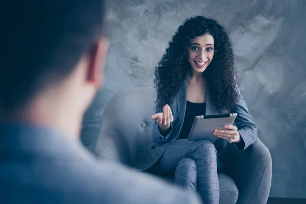 Portrait of her she nice-looking attractive lovely skilled experienced cheerful wavy-haired girl psychologist sitting in chair giving consultation center gray concrete wall background — Stock Photo, Image