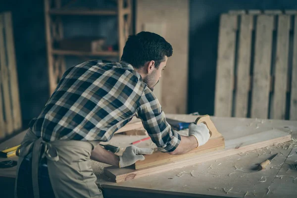 Foto de la tabla de pulir del carpintero trasero de la visión trasera confiada seria para utilizarla para hacer nuevos muebles en guantes —  Fotos de Stock