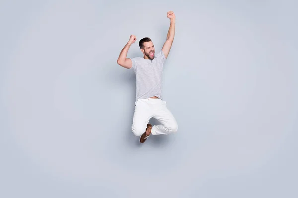 Full length body size view of his he nice attractive sporerful cheerful glad fit bearded guy jumping up rejoicing isolated over light grey pastel color background — стоковое фото