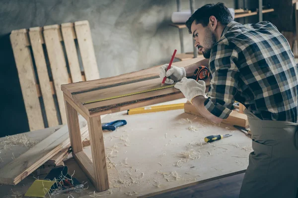 Profiel zijkant achterzijde foto van gerichte werkman te herstellen hobby houten meubelplaat tafel maatregel lengte oppervlak schrijven potlood in huis garage — Stockfoto