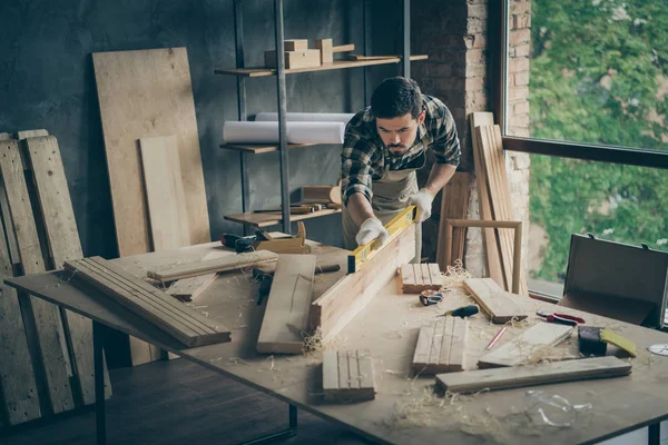 Portrait of his he nice attractive serious focused experienced skilled guy student practicing checking smoothness plank board on table desk at modern industrial loft style interior — Stock Photo, Image