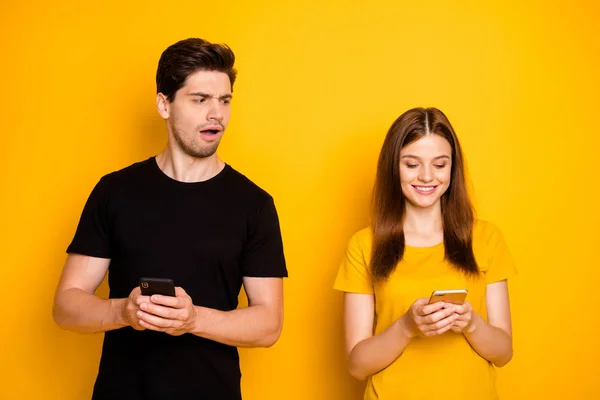 Foto de casal com namorado suspeitando de sua menina de conversar com outros caras e namorada não percebendo seu homem assistindo-a falar vestindo t-shirt preta isolado fundo de cor vívida — Fotografia de Stock