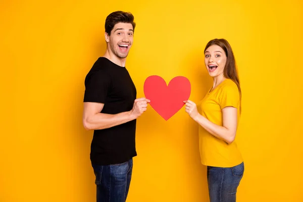 Photo of brunet haired cheerful positive cute sweet pretty beautiful couple wearing black t-shirt jeans denim holding red big heart expressing emotions of love isolated vivid color background — Stock Photo, Image