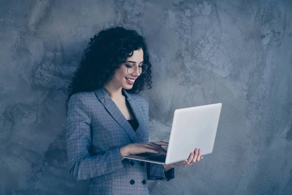 Portrait of her she nice attractive lovely gorgeous chic cheerful cheery confident wavy-haired girl using digital laptop isolated over gray concrete wall background — Stock Photo, Image