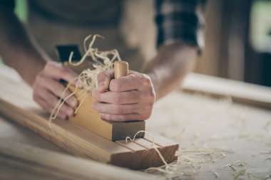 Cropped close-up view of his hands hardworking builder repairman specialist expert entrepreneur making home decor carving wood developing project on table desk clipart