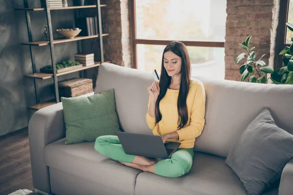 Full length photo of positive cheerful girl sit divan legs crossed use computer want buy new dress use plastic card easy payment concept in house indoors — Stock Photo, Image