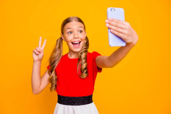 Kuva melko innoissaan pieni nainen tilalla puhelin nuori vaikuttaja joten selfietä blogi osoittaa v-merkki symboli kulumista rento punainen valkoinen mekko eristetty kirkkaan keltainen väri tausta — kuvapankkivalokuva