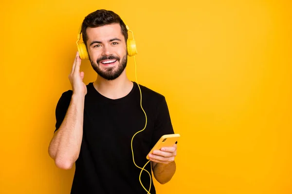 Portrait of funky guy have spring weekends listen music from cell phone use headset copyspace enjoy wear good looking isolated over yellow color background