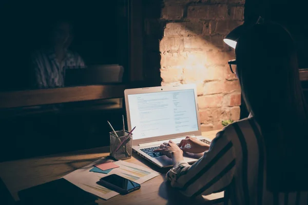 Hátul nézet fotó ázsiai üzletasszony néz notebook képernyő asztal írni új projekt kreatív ötlet kezek billentyűzet ülés szék kopás csíkos ing éjszaka sötét modern iroda — Stock Fotó