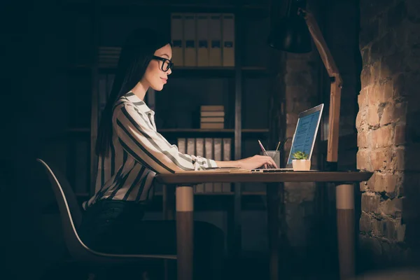 Фото удивительной азиатской деловой леди, смотрящей на экран ноутбука на письменном столе, сообщают о новом проекте сидящего кресла в полоску рубашки с формальной одеждой ночью темный современный офис — стоковое фото
