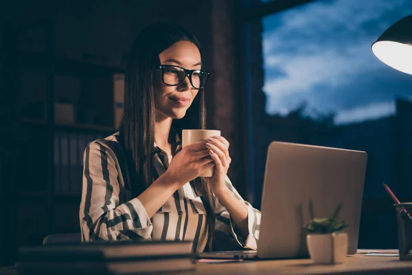 Foto dell'imprenditore che beve bevanda calda negli occhiali guardando nel computer portatile godendo aroma di caffè appena preparato — Foto Stock