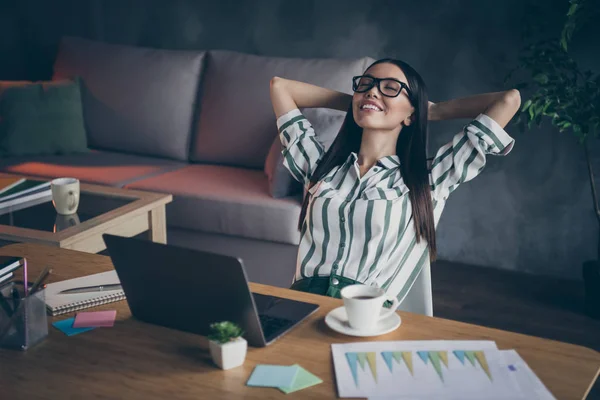 Foto veselé relaxační dívka, která odpočívá na svém pracovišti, usmívá se zubatě ležící na rukou za hlavou v brýlích — Stock fotografie