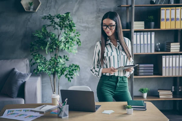 Fotografie veselého zájmu přemýšlivý myšlení žena na sobě zelené kalhoty brýle při pohledu do notebooku drží tablet elektronické zařízení pracující pro významné korporace — Stock fotografie