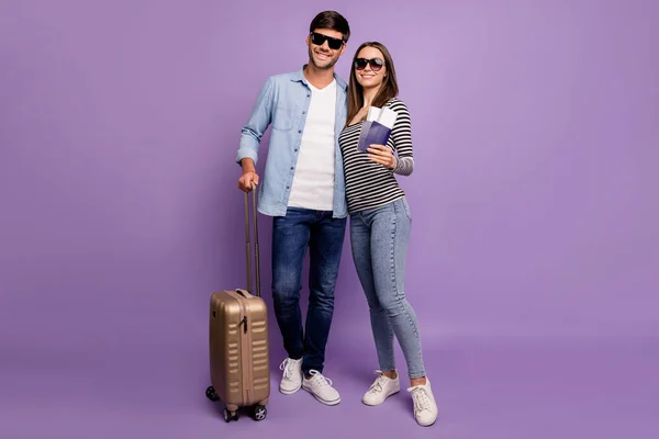 Full length photo of two people couple guy lady walking airport registration tickets passports baggage vacation time wear stylish casual clothes isolated pastel purple color background — Stok fotoğraf