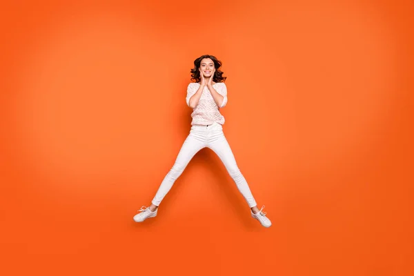 Full size photo of positive cheerful girl have fun on spring time weekends jump touch face hands wear good looking clothing isolated over orange color background — Stock Photo, Image