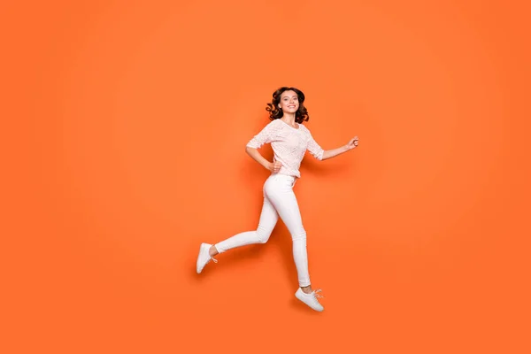 Фотография позитивной жизнерадостной девушки в профиле в полный рост, которая бежит после скидок после распродажи, выглядит спортивно, носит красивый наряд оранжевого цвета — стоковое фото