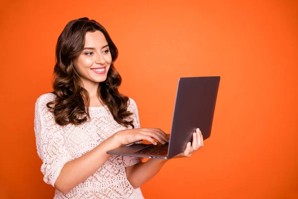 Portrait de fille gaie positive utiliser son ordinateur avoir une conversation en ligne avec un ami sur les médias sociaux compte porter belle tenue isolée sur fond de couleur orange — Photo