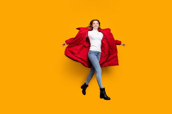 Full length φωτογραφία της γοητευτικής κυρίας άλμα υψηλό περπάτημα δρόμο καταπληκτική ηλιόλουστη μέρα του φθινοπώρου φορούν τζιν παπούτσια λευκό πουλόβερ κόκκινο μακρύ παλτό χειμώνα απομονωμένο κίτρινο χρώμα φόντο — Φωτογραφία Αρχείου