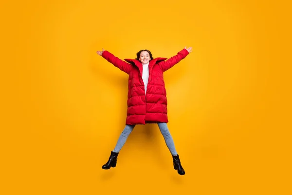 Full length photo of pretty lady jumping high spread hands star shape best weekend wear jeans shoes white pullover red long winter coat isolated yellow color background — Stock Photo, Image