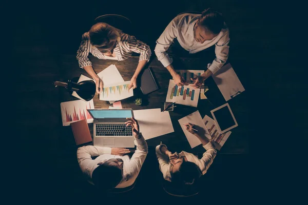 Hohe Winkel über Ansicht Foto von vier Geschäftspartnern sitzen gegenüber Tisch zusammen spätabends diskutieren neue Start-up-Details Formalwear Lampenlicht drinnen — Stockfoto