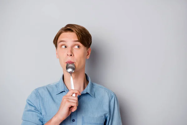 Diner time concept. Funky guy starving wait meal think thoughts what yummy supper his mother prepare lick spoon look copyspace wear stylish clothes isolated grey color background Stock Photo