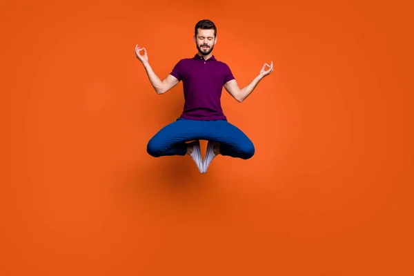 Full size lunghezza del corpo foto di concentrato mentalità uomo premuroso seduto facendo yoga mentre salta su in pantaloni blu isolato sfondo di colore vivido — Foto Stock