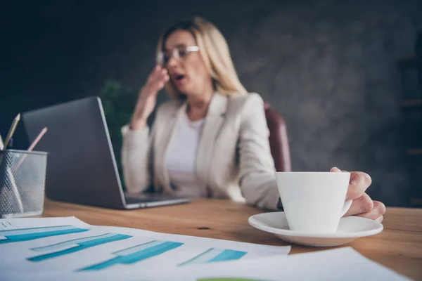 Recortado de cerca la foto de la señora de negocios bostezando cansado sosteniendo la taza de café para despertar y empezar a trabajar por la mañana — Foto de Stock