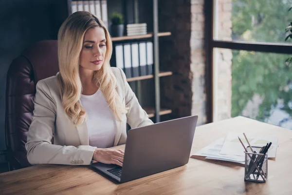 Photo of serious pondering business consulter browsing through her laptop in search of new customers and clients to be recruited — Stock Photo, Image