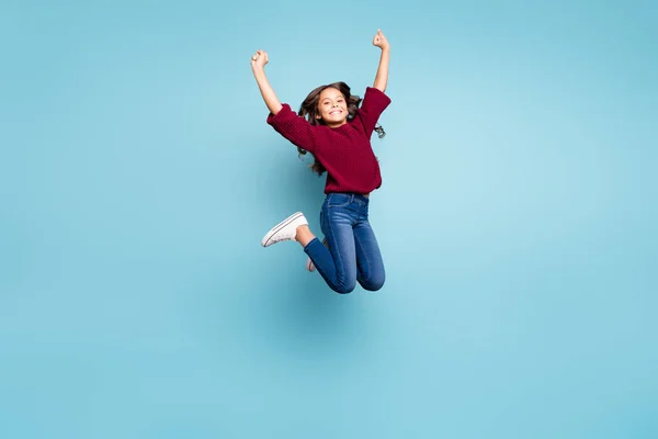 Longitud completa tamaño del cuerpo foto de positiva alegre chica rizada saltando con vaqueros vaqueros sonriendo toothily aislado vívido color azul fondo —  Fotos de Stock