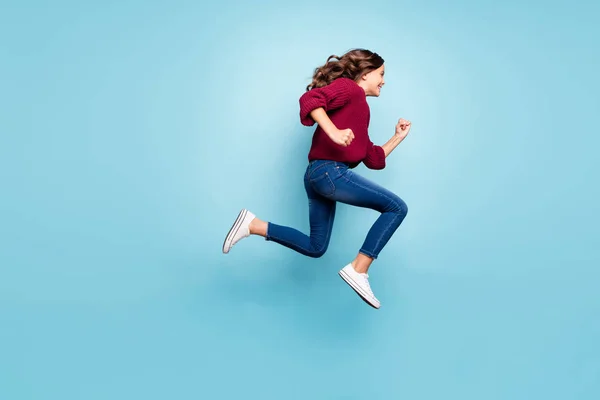 Full length body size photo of curly wavy cheerful trendy preteen wearing jeans denim burgundy sweater running jumping towards shopping mall isolated vivid blue color background — Stock Photo, Image