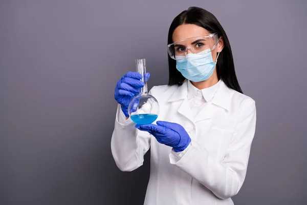 Retrato de cientista bem sucedido mulher apresentar sua nova medicação contra o câncer que ela segura em seu frasco azul líquido usar luvas de segurança óculos branco casaco máscara isolado cinza cor fundo — Fotografia de Stock