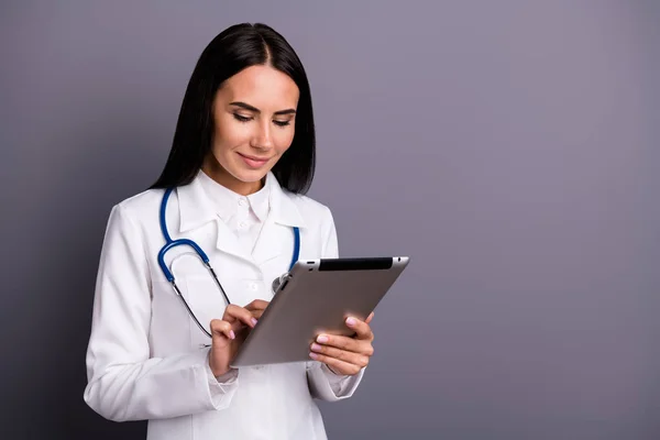 Porträt von fokussierten braunen Haaren Arzt Mädchen konsultieren Patient verwenden Tablette Suche lesen Kardiologie Informationen tragen weißen Mantel einheitliche Stethoskop isoliert graue Farbe Hintergrund — Stockfoto