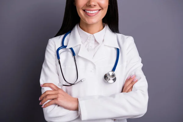 Foto recortada de cabello castaño experimentado niña médico trabajo en el hospital manos cruzadas listo consultar a los pacientes usan estetoscopio blanco abrigo aislado sobre fondo de color gris — Foto de Stock