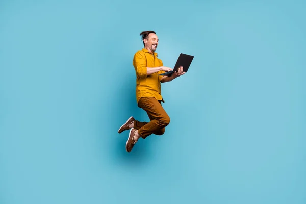 Full tělo foto veselý vzrušený muž skok použít počítač vyhledávání on-line sociální média černá pátek prodej slevy nosit ležérní styl oblečení izolované přes modré barvy pozadí — Stock fotografie