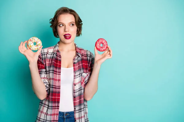 Güzel bir kızın portresi iki donut tutar nefis bir tadı olduğunu düşünür dudakları yalar tatlı aşıklar sağlıklı beslenme konsepti günlük kıyafet giyer izole turkuaz rengi deniz mavisi arka plan — Stok fotoğraf