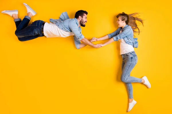 Top view above high angle flat lay flatlay lie full length body size view concept of cheery beautiful handsome spouse holding hand flying isolated on bright vivid shine vibrant yellow color background — 스톡 사진