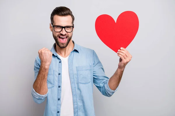 Foto de loco contento chico guapo sosteniendo gran corazón de papel rojo chica bonita lo invitó a fiesta de graduación lleno de alegría desgaste especificaciones traje de mezclilla casual aislado fondo de color gris —  Fotos de Stock