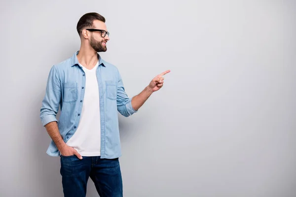 Foto do negócio cara atraente bom humor indicando dedo espaço vazio mostrando novidade produto propaganda desgaste especificações casual ganga roupa isolado cinza cor fundo — Fotografia de Stock