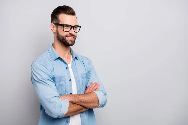 Foto de chico atractivo joven jefe promovido manos cruzadas confianza en sí mismo persona amable sonrisa mirada espacio vacío desgaste especificaciones traje de mezclilla casual aislado fondo de color gris —  Fotos de Stock