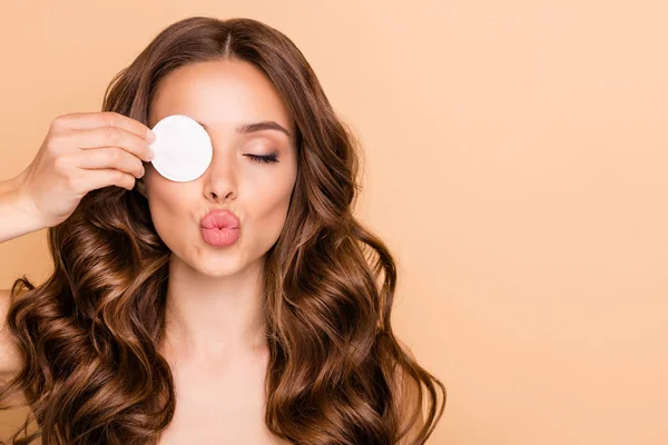 De cerca la foto de la encantadora dama de pelo rizado aplicar loción limpiadora para que su piel clara en el salón de spa eliminar los cosméticos de sus ojos utilizar parche de algodón aislado sobre fondo de color beige — Foto de Stock