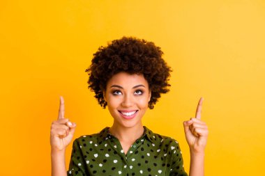 Close up photo of positive cheerful afro american girl promoter point index finger copy space indicate look adverts promotion wear stylish clothes isolated yellow color background clipart