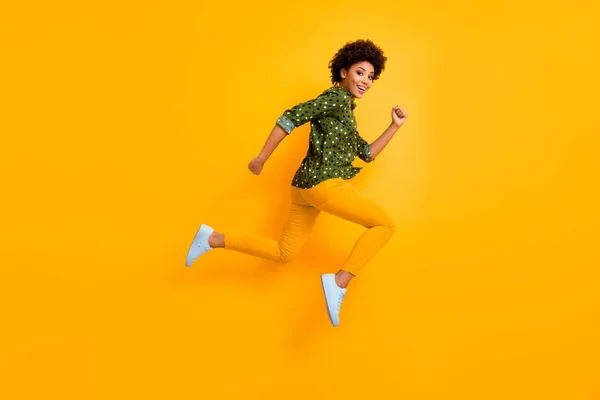 フルサイズの写真のクレイジー黒肌巻き女性ジャンプアップ高急いで高速割引ショッピング黒金曜日低価格着用緑点線シャツパンツシューズ隔離された黄色の色の背景 — ストック写真