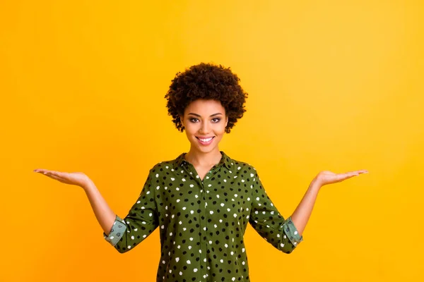 Ritratto di positivo allegro afro americano ragazza tenere mano pubblicizzare annunci promo dimostrare sconto vendite indossare abito elegante isolato su sfondo di colore brillante — Foto Stock