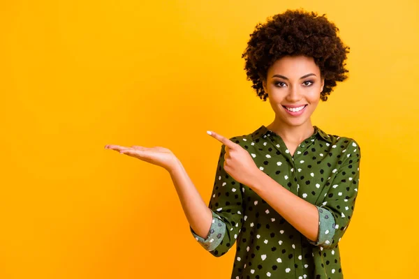 Ritratto di positivo afro americano ragazza tenere mano punto indice dito presente annunci di promozione consiglia di selezionare scegliere di consigliare indossare abiti alla moda isolato colore giallo sfondo — Foto Stock