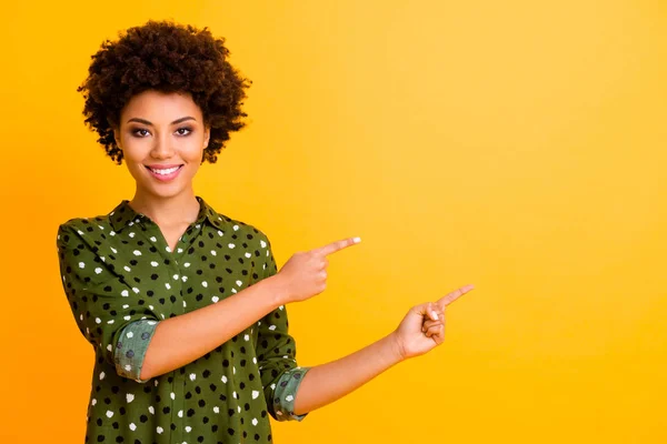 Porträtt av positiva afro amerikanska flicka peka pekfinger kopiera utrymme närvarande annonser rekommendera marknadsföring föreslå välja feedback försäljning bära snygga kläder isolerad gul färg bakgrund — Stockfoto
