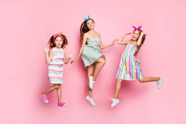 Full storlek foto av vackra syskon hoppa bär ljusa kjol klänning pannband isolerad över rosa bakgrund — Stockfoto