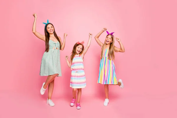 Volledige lengte foto van vrolijke meisjes met lang haar geknipt met hoofdbanden verhogen vuisten schreeuwen ja vieren overwinning dragen rok jurk geïsoleerd over roze achtergrond — Stockfoto