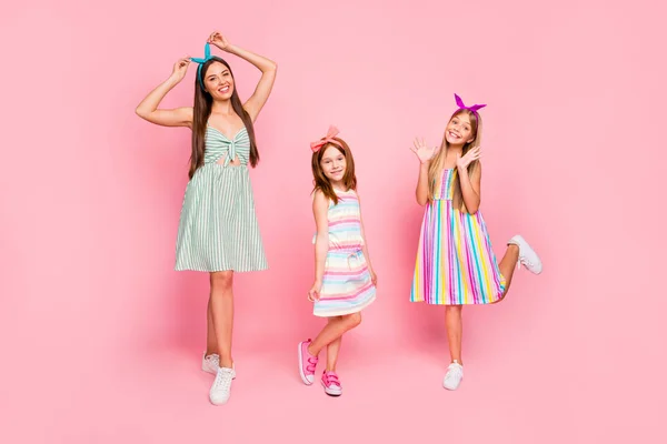 Foto de tamaño completo de damas bonitas con diademas brillantes disfrutando posando usando falda de vestido aislada sobre fondo rosa —  Fotos de Stock